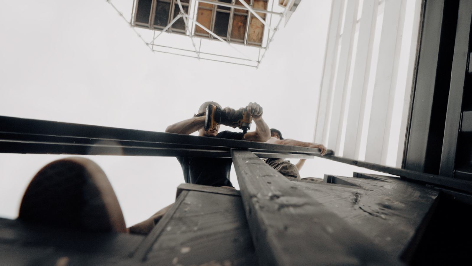 Looking straight up at a builder drilling a rail from below