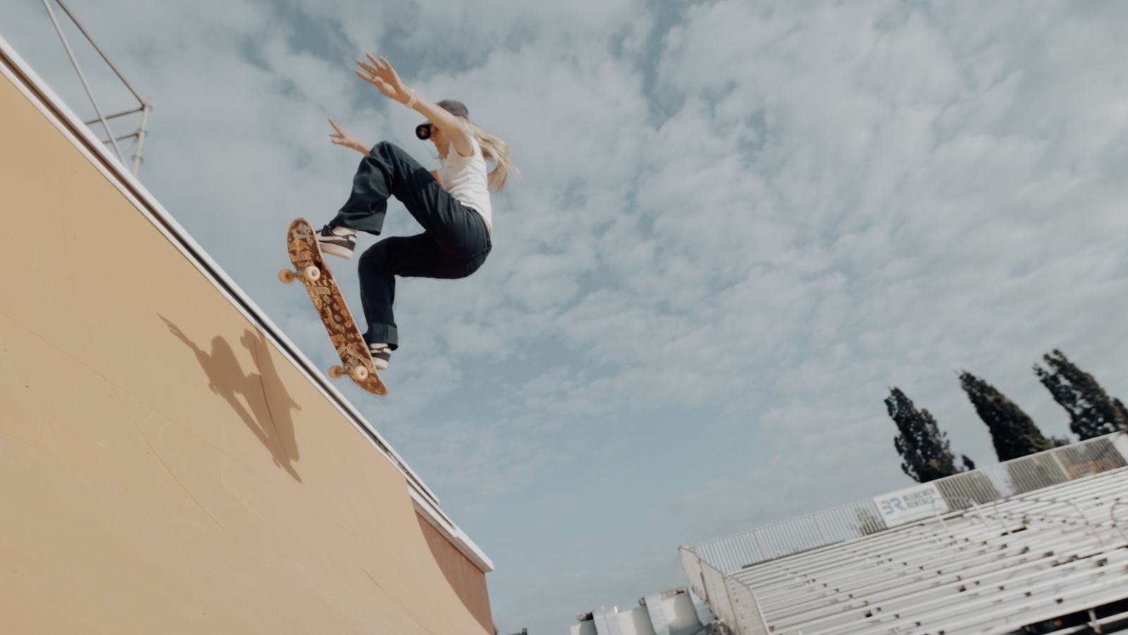 Skater launching off the quarter pipe with her shadow on the ramp
